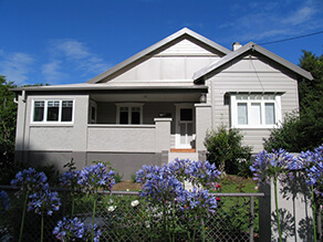 Grey Neutral Weatherboard with Contrasting Dark Grey Trims and White Window Sills and Garden